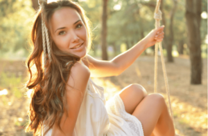 woman is swinging on a swing in summer pine forest